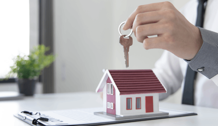 Persona sostiene una llave sobre la maqueta de una casa